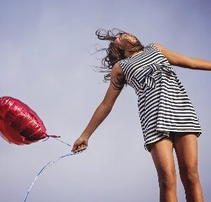 een vrouw die van blijdschap in de lucht springt met een ballon, omdat ze haar energiemanagement op orde heeft