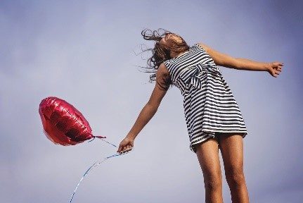 een vrouw die van blijdschap in de lucht springt met een ballon, omdat ze haar energiemanagement op orde heeft